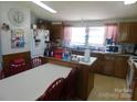 Country kitchen with wood cabinets, a white refrigerator, an island and a dining area with red chairs at 33343 Old Salisbury Rd, Albemarle, NC 28001