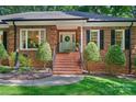 Inviting brick entrance with a classic white door, complemented by meticulously maintained landscaping at 5008 Saddle Horn Trl, Weddington, NC 28104