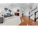 Cozy living room with hardwood floors, a gray sofa, and staircase at 7612 Turley Ridge Ln, Charlotte, NC 28273