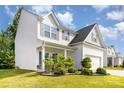 Well-maintained two-story home featuring white siding, a covered porch, lush landscaping, and a two-car garage at 8330 Kneller St, Charlotte, NC 28215