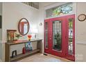 Bright entryway featuring a decorative red front door, console table, and tile flooring at 9141 Covey Hollow Ct, Charlotte, NC 28210