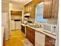 Functional kitchen with white appliances and wood cabinets, adjacent to laundry area at 1010 Macarthur Rd, Albemarle, NC 28001