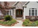 Close-up of the front entrance with a stone archway, double doors, manicured landscaping, and charming details at 1687 Sierra Rd, York, SC 29745