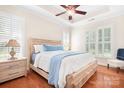Bright main bedroom featuring a tray ceiling, wood floors, shutters, and a comfortable king-size bed at 407 Knops Nob Rd, Mooresville, NC 28115