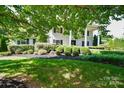 View of the home's symmetrical facade, surrounded by mature landscaping and lush greenery at 711 Yadkin St, Albemarle, NC 28001