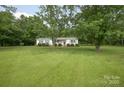 Quaint ranch-style home with lush green lawn shaded by mature trees at 7645 Robinson Church Rd, Harrisburg, NC 28075
