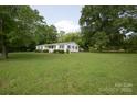Ranch-style home featuring a lush green lawn and mature shade trees at 7645 Robinson Church Rd, Harrisburg, NC 28075