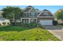 Beautiful brick home with manicured lawn, vibrant flower beds, and a two-car garage on a sunny day at 8325 Burgundy Ridge Dr, Harrisburg, NC 28075