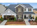 Stylish two-story home featuring brick and gray siding with a well-maintained lawn, and rocking chairs on the front porch at 1045 Waxhaw Crossing Dr, Waxhaw, NC 28173