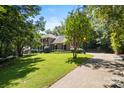 Brick home with a long driveway, surrounded by a lush green lawn and mature trees at 1134 Willow Oaks Trl, Matthews, NC 28104