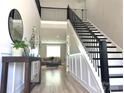 Elegant foyer with hardwood floors, staircase with black railing, and a view into the living area at 305 Pleasant Hill Se Dr, Concord, NC 28025