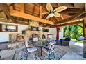 Inviting outdoor kitchen with a stone fireplace, TV, ceiling fan, and dining space for outdoor enjoyment at 3981 Spinnaker Pl, Denver, NC 28037