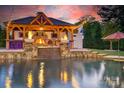Gorgeous pool with an outdoor kitchen featuring a built-in stone fireplace and stylish bar seating at 3981 Spinnaker Pl, Denver, NC 28037