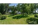 Scenic view of a home partially shaded by mature trees, featuring a well-maintained lawn, offering a tranquil outdoor space at 5560 Springs Rd, Conover, NC 28613