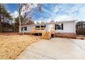 The home features a concrete driveway, wooden porch and is set amongst trees and greenery at 716 Sharon Ln, Iron Station, NC 28080