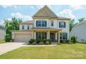 Beautiful two-story home with blue shutters, a covered front porch, and lovely landscaping at 10437 Paper Birch Dr, Charlotte, NC 28215