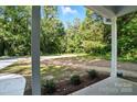 A view from the front porch overlooking the landscaped yard with mature trees in the background at 411 Patience Dr, Concord, NC 28025