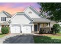Charming home features a two-car garage, stone accents, and a well-maintained front yard under a colorful sky at 9644 Marquette Nw St, Concord, NC 28027