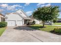Charming home features a two-car garage, stone accents, and a well-maintained front yard under a bright sky at 9644 Marquette Nw St, Concord, NC 28027