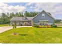Beautiful home with blue siding, stone accents, green lawn and mature trees in the background at 307 Stoneyard Rd, Richfield, NC 28137