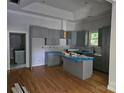 Kitchen with modern gray cabinets, an island, and elegant backsplash, seamlessly flowing into the living space at 409 Everette St, Monroe, NC 28112