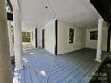 A covered porch showcasing wood flooring, classic columns, and black trim at 409 Everette St, Monroe, NC 28112