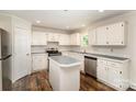 Well-lit kitchen with white cabinetry, stainless steel appliances, and a center island, complemented by durable laminate floors at 508 Bridgestone Ln, Rock Hill, SC 29730