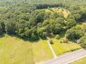 Aerial view of a property showcasing its serene setting amidst lush greenery and nearby fields at 6115 Campbell Rd, York, SC 29745
