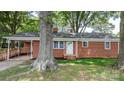 Charming brick house with a white door, surrounded by mature trees and a carport at 151 Third Creek Rd, Statesville, NC 28677