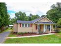 Single-story home with well-manicured lawn, charming red shutters, and a cozy porch with seating at 218 Blacksnake Rd, Stanley, NC 28164