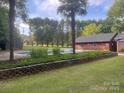 Backyard pool features mature trees, a brick retaining wall, and a charming cabana at 4050 Rollingwood Cir, Rock Hill, SC 29732