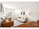 Cozy living room with a white sofa, natural light, a decorative rug, and warm leather seating at 6507 Revolutionary Trl, Charlotte, NC 28217