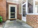 Inviting brick entryway with a storm door and an adjacent glass-enclosed porch at 8465 Olde Troon Dr, Charlotte, NC 28277