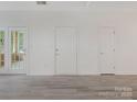 Bright living room with fresh white paint, multiple doors, and modern gray floors at 8465 Olde Troon Dr, Charlotte, NC 28277
