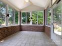 Sunroom with brick walls, tile floors, ceiling fan and many windows offering backyard views at 8465 Olde Troon Dr, Charlotte, NC 28277