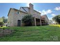 The rear exterior showcasing a brick facade, wooden deck, and lush green lawn under a sunny sky at 1335 33Rd Avenue Ne Dr, Hickory, NC 28601