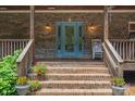 Close-up of a welcoming front porch with a decorative blue front door and brick steps at 260 River Country Rd, Salisbury, NC 28146
