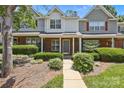 Well-maintained townhome featuring a brick facade, lush greenery, and cozy front porch at 5724 Cougar Ln, Charlotte, NC 28269