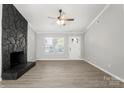 Bright living room features a ceiling fan, new floors and a stone fireplace at 6515 Santa Cruz Trl, Charlotte, NC 28227