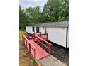 This well-maintained mobile home has a metal roof, a ramp, and a small porch painted a vibrant red at 6517 Helens Way, Denver, NC 28037