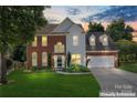 Charming brick and siding home featuring a well-manicured lawn and two-car garage at dusk at 8000 Pelorus Ln, Charlotte, NC 28269