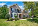 Traditional two-story brick home with mature trees, lush lawn, and welcoming front porch at 10104 Treetop Ln, Cornelius, NC 28031