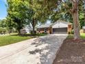 View of the front of the home with an extended driveway and mature trees in the front yard at 1115 Berry Ridge Rd, Charlotte, NC 28270