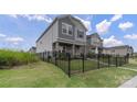 Gray siding two-story home featuring a landscaped yard enclosed by black metal fence at 135 Orson Oaks Ln, Pineville, NC 28134