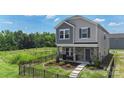 Two story home with gray siding, stone facade and a well manicured front yard with black metal fencing at 135 Orson Oaks Ln, Pineville, NC 28134