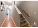 Inviting hallway features wood floors, stairs with carpet, and neutral paint, creating a warm and welcoming atmosphere at 14755 Lions Paw St, Charlotte, NC 28273
