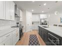 Modern kitchen with white cabinets, stainless steel appliances, a large island with pendant lighting, and wood floors at 1517 Falcon St, Charlotte, NC 28211