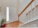 Bright foyer with hardwood floors and a staircase that offers a view of the front door and a hint of natural light at 1930 Caprington Dr, Fort Mill, SC 29707