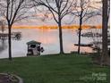 Scenic lake view featuring a boathouse and the tranquil water reflecting the sunset colors at 2704 Apache Trl, Denver, NC 28037
