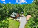 Aerial view of cozy home nestled within lush, mature trees, a circular driveway, and a sprawling green lawn at 485 Johnson St, China Grove, NC 28023